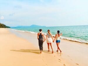 Women walking hand in hand on the beach.